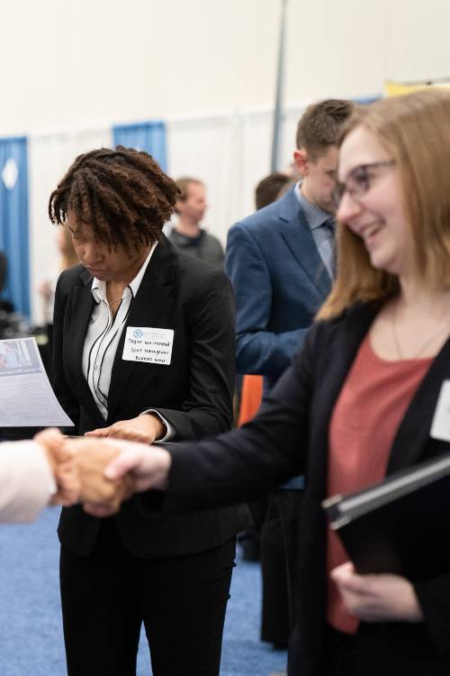 Four people in business attire shaking hands